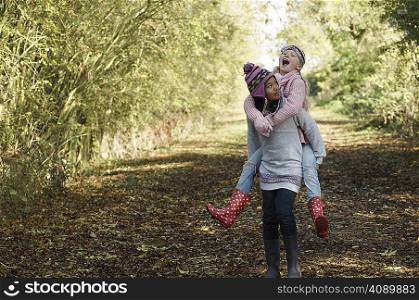 Girl carrying friend in countryside