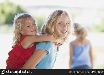 Girl carrying younger sister piggyback