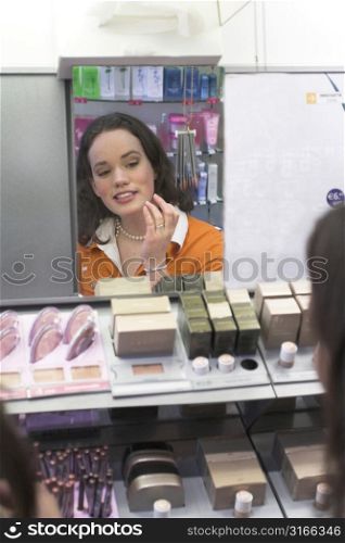 Girl checking her new colour lipstick in the shop mirror
