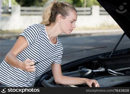 girl checks the oil in the cars engine