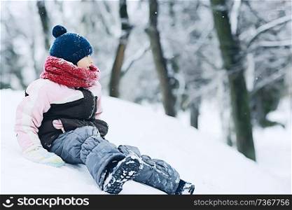 girl child rolls in winter with a snow roller coaster / happy childhood concept, entertainment outside. Sports, mountains, snow. Winter happiness for children. Immunity, health, warm clothes.