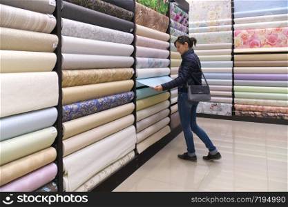 Girl chooses wallpaper in the store marketplace.