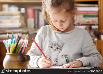 Girl coloring on paper having creative time at home