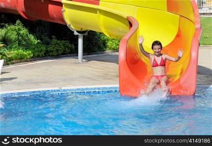 girl comes down the slide into the pool