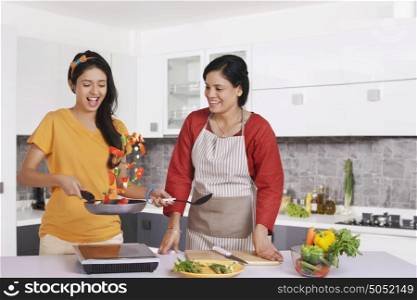 Girl cooking food while mother watches on
