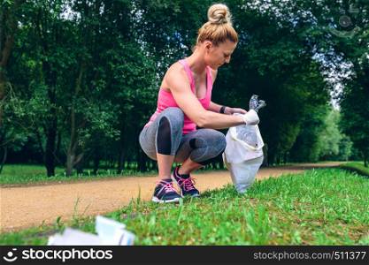 Girl crouching with bag picking up trash doing plogging. Girl picking up trash doing plogging