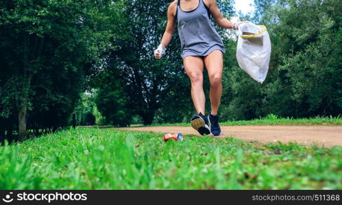 Girl crouching with garbage bag doing plogging outdoors. Girl with garbage bag doing plogging