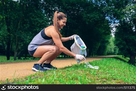Girl crouching with garbage bag doing plogging outdoors. Girl with garbage bag doing plogging