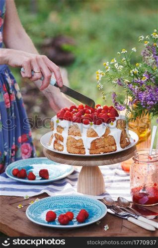 girl cuts biscuit with strawberries. dining table in the garden.