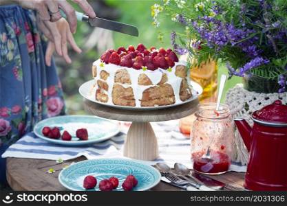 girl cuts biscuit with strawberries. dining table in the garden. Still life