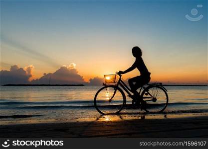 Girl cycling in the sea during sunrise