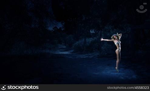 Girl dancing in dark. Young girl in white swim wear dancing in night