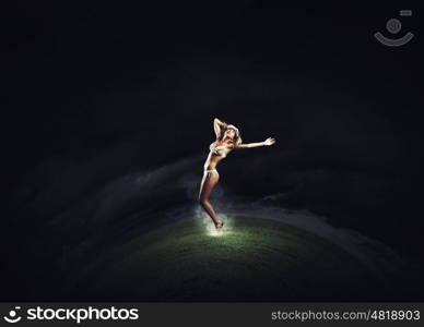 Girl dancing in dark. Young girl in white swim wear dancing in night