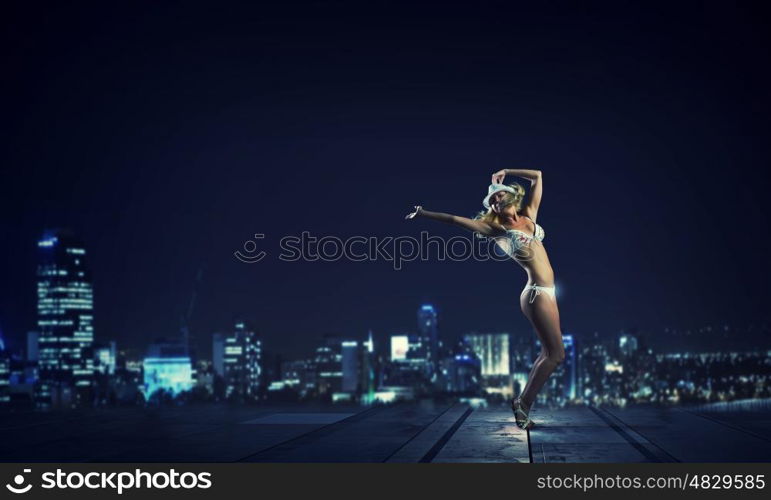 Girl dancing in dark. Young girl in white swim wear dancing in night