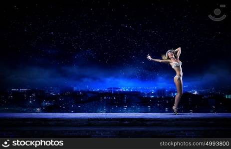 Girl dancing in dark. Young girl in white swim wear dancing in night