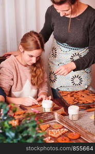 Girl decorating baked Christmas gingerbread cookies with frosting writing pen