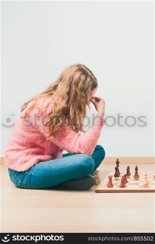 Girl deeply thinking about next move during chess game. Copy space for text at the top and bottom of image
