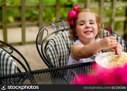 Girl dining at garden table looking at camera smiling