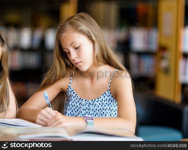 Girl doing her homework in library. Time to do my homework