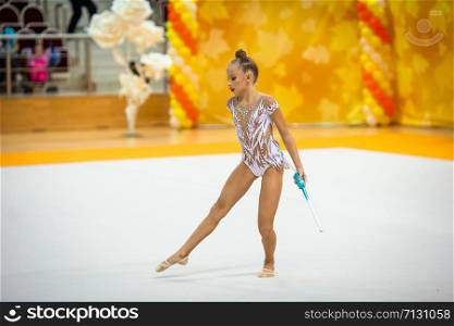 Girl doing rhythmic gymnastics with maces. Beautiful little active gymnast girl with her performance on the carpet