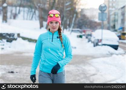 Girl doing urban workout during winter. Lady exercising on snowy streets. Health fitness fashion concept. . Girl doing urban workout during winter