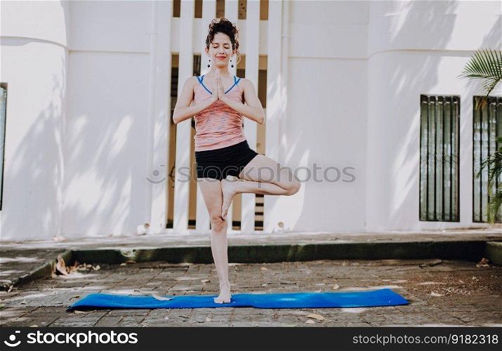 Girl doing yoga vrikshasana or tree pose outdoors. Young woman doing vrikshasana yoga outdoors. Relaxation and vitality yoga concept
