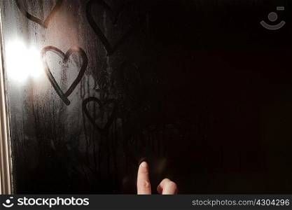 Girl drawing heart shape in condensation on window
