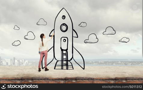 Girl drawing rocket. Young student girl standing with back and drawing rocket