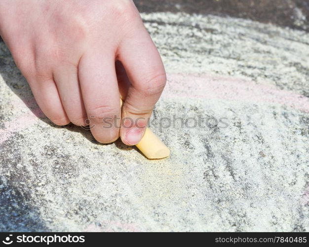 girl drawing with colored crayons on pavement on street close up