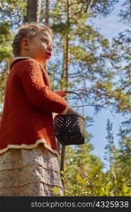 Girl dressed in retro clothing with basket in forest