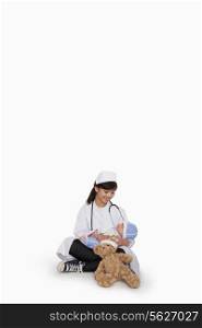 Girl dressed up as doctor with teddy bear and doll