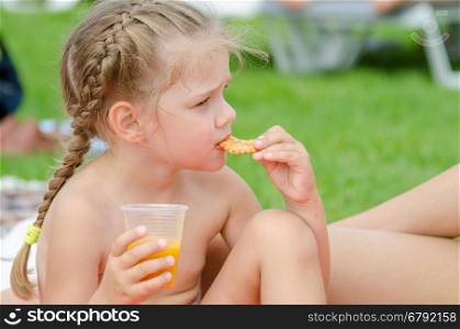 Girl eating cookies and drinking juice from a plastic disposable cup