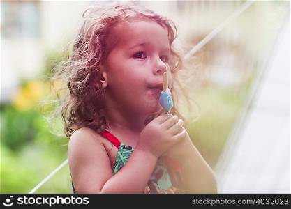 Girl eating melting ice lolly in garden