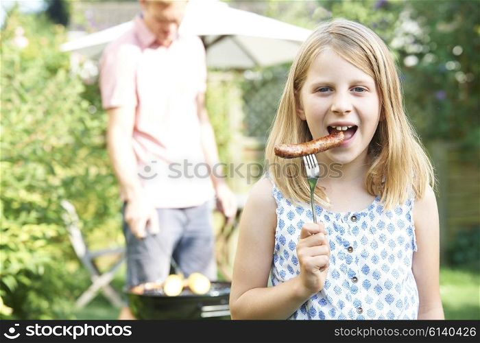 Girl Eating Sausage At Family Barbeque