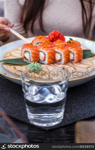 Girl eating sushi. Fresh sushi on a platter is cooled with ice.