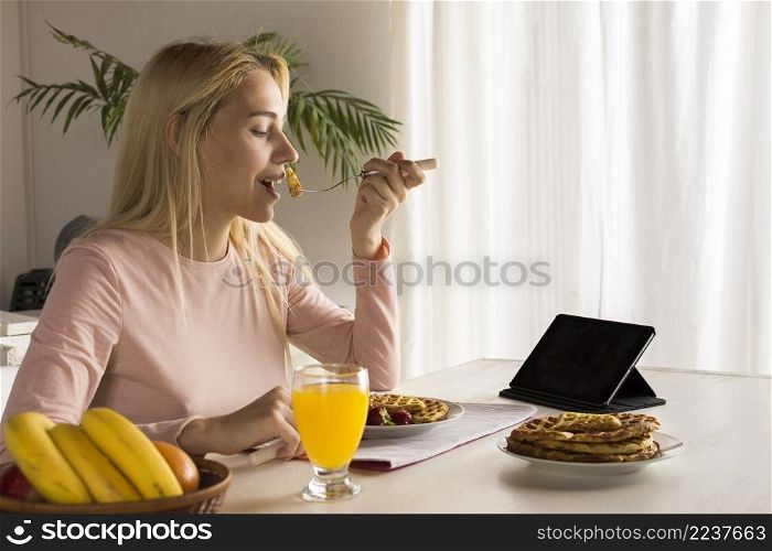 girl eating waffles watching tablet