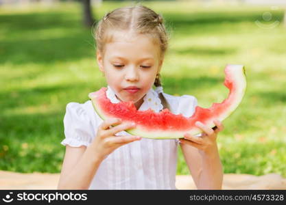 Girl eating watermelon. Cute girl in park eating juicy watermelon