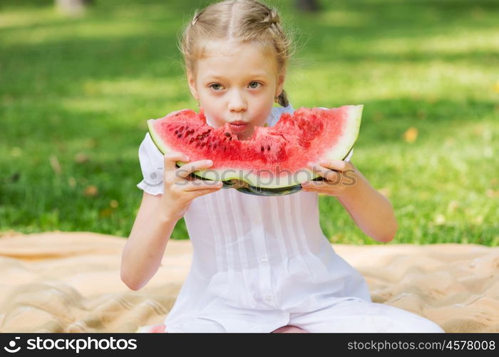 Girl eating watermelon. Cute girl in park eating juicy watermelon