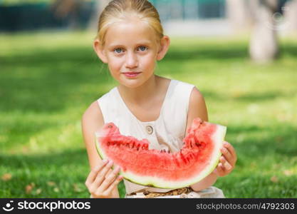 Girl eating watermelon. Cute girl in park eating juicy watermelon