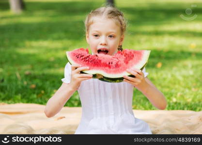 Girl eating watermelon. Cute girl in park eating juicy watermelon