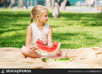 Girl eating watermelon. Cute girl in park eating juicy watermelon