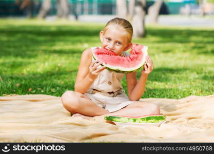 Girl eating watermelon. Cute girl in park eating juicy watermelon