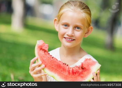 Girl eating watermelon. Cute girl in park eating juicy watermelon