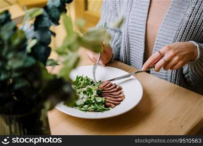 girl eats warm salad with a cutting of a duck
