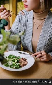 girl eats warm salad with a cutting of a lamb