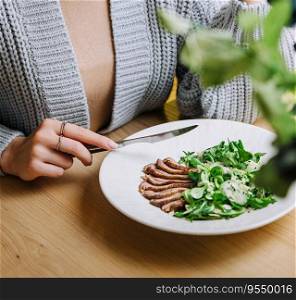 girl eats warm salad with a cutting of a lamb