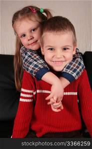 girl embraces boy for the neck on sofa