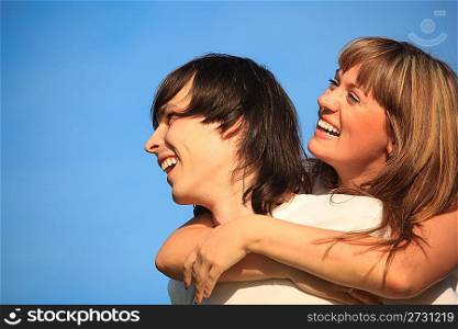 girl embraces guy behind for neck against sky
