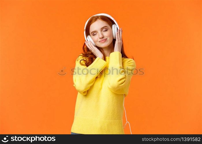 Girl enjoying nice soft sound of headphones. Cheerful romantic and delighted pretty redhead woman tilt head with closed eyes and tender smile, carried away with music in earphones.. Girl enjoying nice soft sound of headphones. Cheerful romantic and delighted pretty redhead woman tilt head with closed eyes and tender smile, carried away with music in earphones