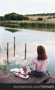 girl enjoying picnic on a wooden pier on a shiny summer river shore